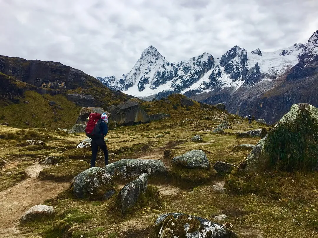 Randonneur sur un sentier des Andes, sommets enneigés au loin